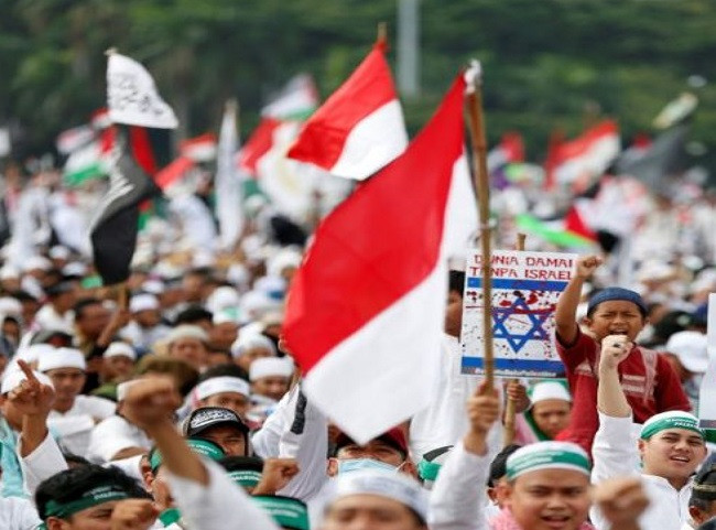 Nhiều người biểu tình mặc đồ trắng, vẫy cờ Indonesia và cờ Palestine. Họ còn mang theo biểu ngữ có nội dung: “Hòa bình, tình yêu và tự do cho Palestine”. Ảnh: Reuters.