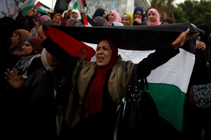 Người phụ nữ cầm lá cờ Palestine trong cuộc biểu tình ở Thành phố Gaza. Ảnh: Reuters.