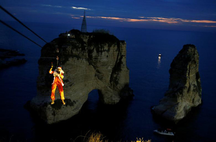 Một ông già Noel đu dây tới Pigeon Rock “Rawshe” để thắp sáng cây thông Giáng sinh ở Beirut, Lebanon. Ảnh: Reuters.
