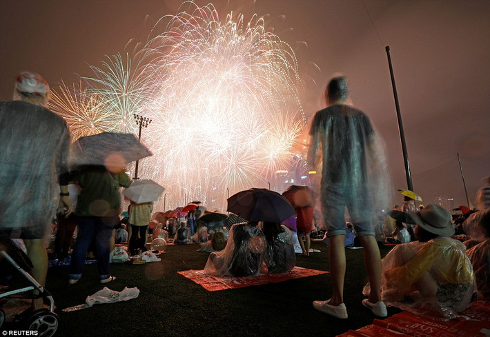 Người dân “đội mưa” ngắm pháo hoa mừng năm mới ở vịnh Marina, Singapore. Ảnh: Reuters.