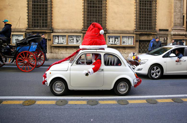 “Ông già Noel” vừa điều khiển xe vừa rung chuông trên đường phố Rome, Italy. Ảnh: Reuters.