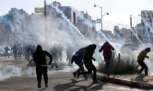 Những người biểu tình Palestine cháy tán loạn để tránh hơi cay của binh sĩ Israel ở khu định cư Do Thái Beit El. Ảnh: Reuters.