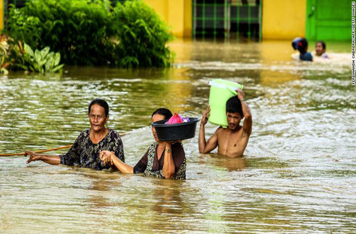 Người dân lội qua con đường ngập nước trên đảo Mindanao. Ảnh: CNN.