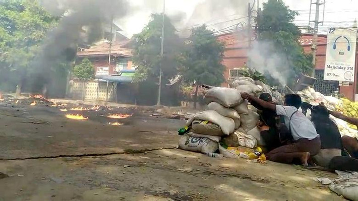 Người biểu tình nấp sau hàng rào bao cát trong đụng độ với lực lượng an ninh Myanmar ở Mandalay, ngày 27/3. Ảnh: Reuters.