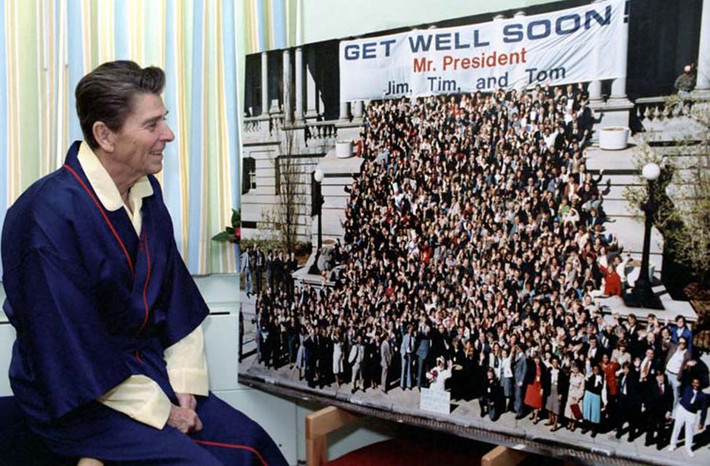 Tổng thống Reagan mỉm cười khi nhìn vào bức ảnh “Get Well Soon Mr. President” (Tam dịch: Mau khỏe nhé, ngài Tổng thống) trong thời gian hồi phục sức khỏe tại bệnh viện George Washington ngày 8/4/1981.