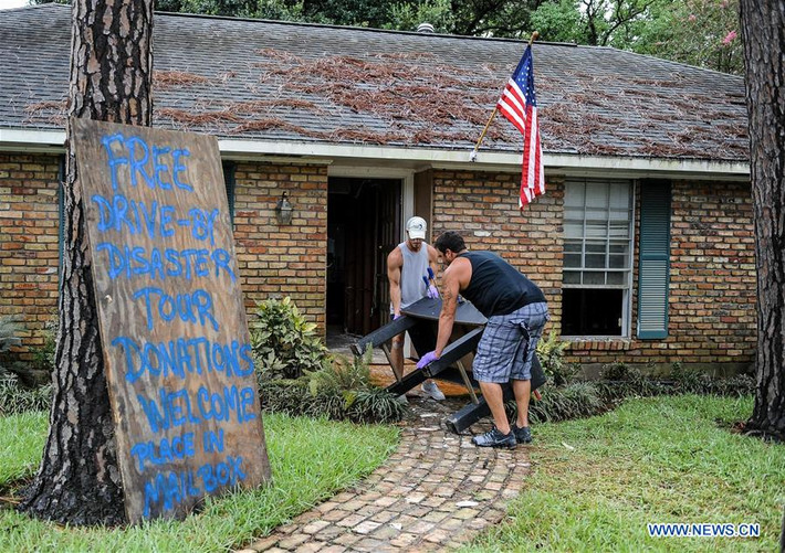 Hai người đàn ông vứt bỏ những đồ đạc bị hư hại do mưa lũ ở Baton Rouge.