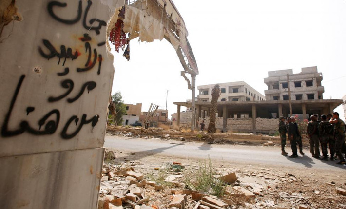 Các binh sĩ chính phủ Syria đứng ở lối vào thị trấn Daraya trước khi bắt đầu sơ tán người dân khỏi thị trấn này. Ảnh: Reuters.