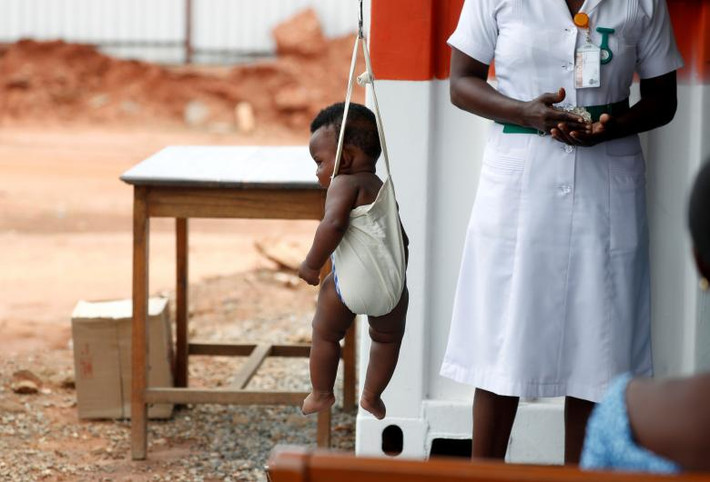 Một em nhỏ đang được cân khi Đệ nhất phu nhân Melania thăm bệnh viện ở Accra.