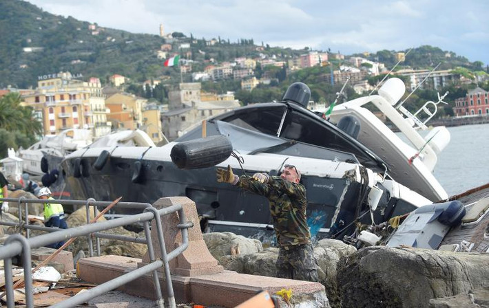 Người đàn ông dọn dẹp đống đổ nát trên một bờ biển ở Rapallo ngày 30/10. Ảnh: Reuters.