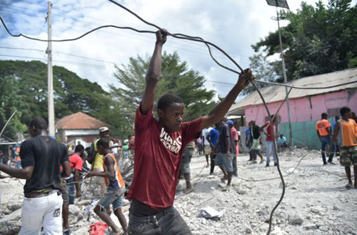 Người dân Haiti thu dọn sau khi một tòa nhà bị phá hủy ở Gros Morne ngày 7/10. Ảnh: Getty.