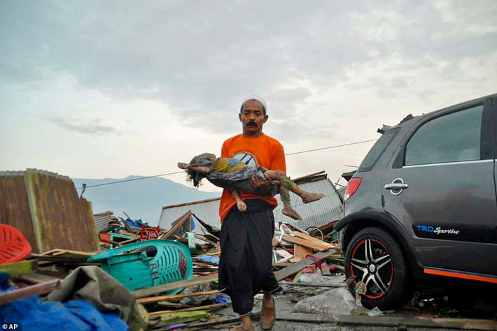 Người đàn ông bế thi thể một em nhỏ thiệt mạng trong trận sóng thần ở Indonesia vừa qua. Ảnh: AP.