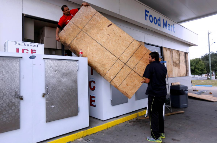 Culwinder Singh và Sukhdeep Uppal gia cố cửa hàng ở Destin, Florida, ngày 9/10. Ảnh: Reuters.