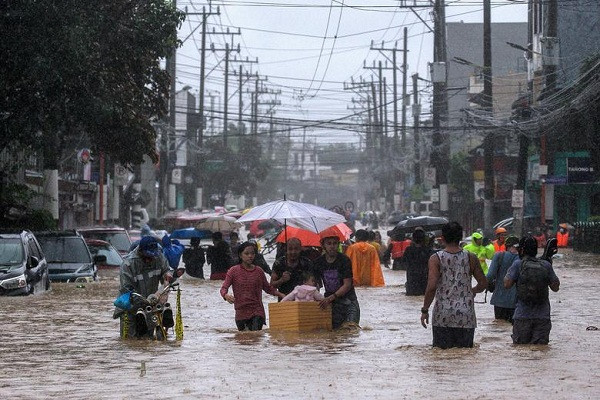 Người dân lội qua con đường ngập lụt đi sơ tán ở Marikina hôm 12/11.