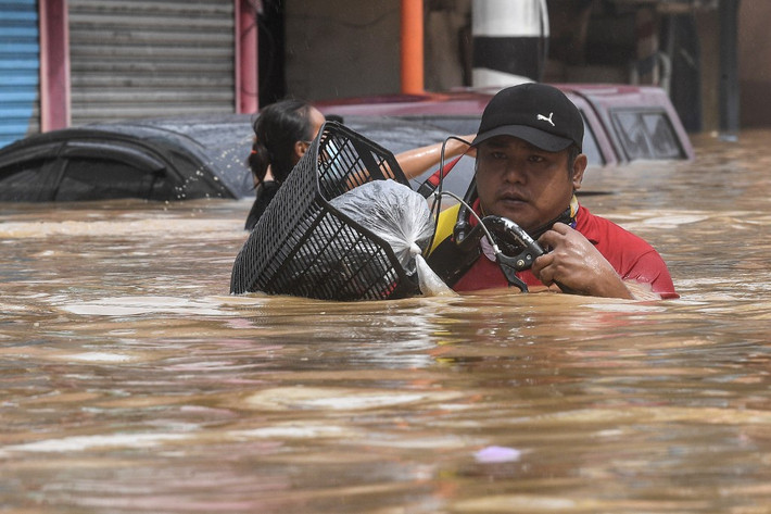 Một người dân lội nước gần đến cổ tại Marikina. Ảnh: AFP.