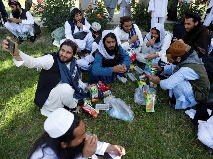Một tù nhân Taliban chụp ảnh "tự sướng" trong khi các thành viên khác ăn bánh và uống nước trong khuôn viên nhà tù Pul-i-Charkhi ngày 26/5.