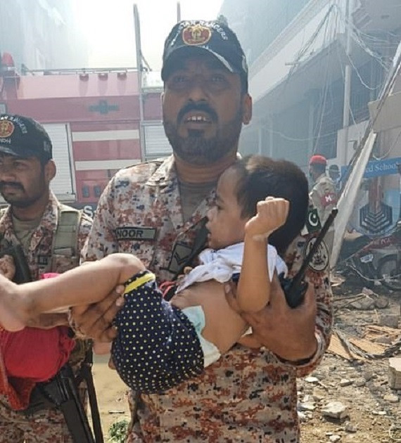 Binh sĩ Quân đội Pakistan đưa một em nhỏ ra khỏi đống đổ nát.