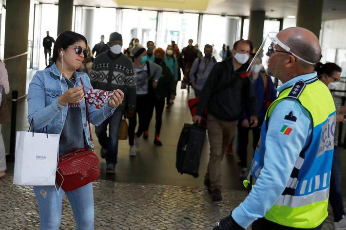 Cảnh sát nhắc nhở một người phụ nữ đeo khẩu trang tại nhà ga Cais do Sodre ở Lisbon, Bồ Đào Nha, ngày 4/5. Bồ Đào Nha cũng quyết định nới lỏng phong tỏa khi tình hình dịch bệnh "hạ nhiệt".