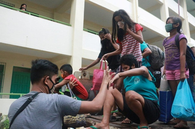 Tuy nhiên, giới chức lo ngại khi nơi trú ẩn tập trung đông người, các biện pháp giãn cách xã hội để tránh virus SARS-CoV-2 lây lan sẽ khó được thực hiện. Ảnh: Người dân đeo khẩu trang được đưa tới một trường học ở Legazpi, tỉnh Albay, để tránh bão. Ảnh: Reuters.