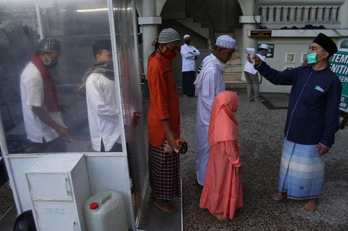 Hôm 23/5 vừa qua, đông đảo người Hồi giáo khắp thế giới đã tổ chức lễ Eid al-Fitr đánh dấu kết thúc tháng Ramadan. Trong dịp lễ này, các tín đồ cũng phải tuân thủ giãn cách xã hội khi cầu nguyện cũng như thực hiện các biện pháp phòng ngừa lây nhiễm virus. Ảnh: Các tín đồ Hồi giáo Indonesia được đo thân nhiệt trước khi vào nhà thờ ở Malang, tỉnh Đông Java, để cầu nguyện hôm 24/5.