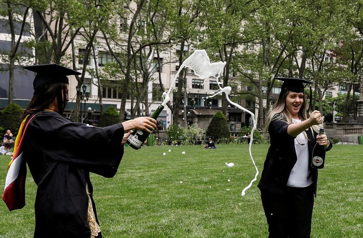 Taylor Laufer và Yuliya Dubyna ăn mừng tốt nghiệp trên bãi cỏ ở Công viên Bryant, New York, Mỹ, ngày 18/5.