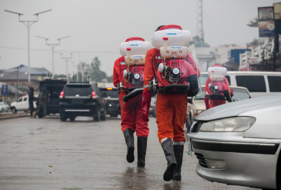 Các nhân viên đi phun thuốc khử trùng trên đường phố ở Nigeria.