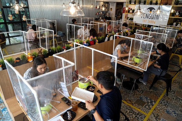Người dân ăn trưa trong nhà hàng Penguin Eat Shabu sau khi nơi này mở cửa trở lại ở thủ đô Bangkok, Thái Lan, ngày 8/5. Có thể thấy các vách ngăn được lắp đặt trên bàn ăn.