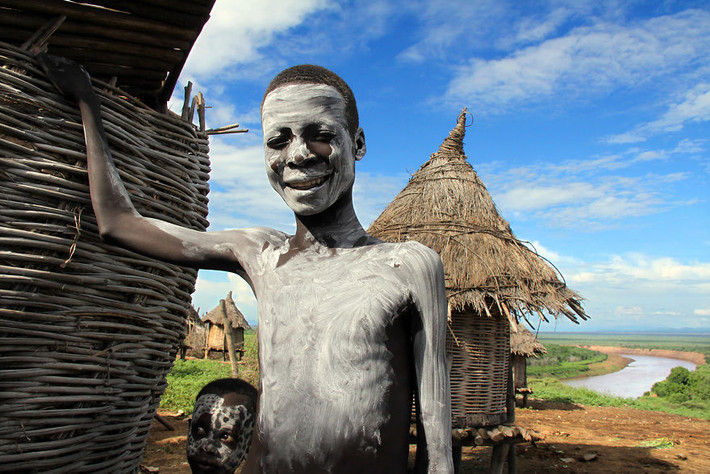Bé trai đứng cạnh ngôi nhà ở Korcho, Ethiopia.
