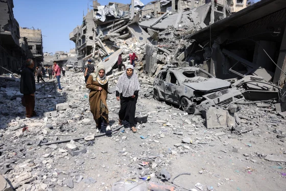 Người dân Gaza đi qua đống đổ nát của một tòa nhà bị phá hủy trong đợt oanh kích của Israel vào tuần trước ở Jabaliya. Ảnh: GI.