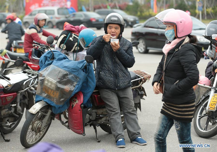 Người đàn ông tranh thủ đứng ăn ngay tại trạm xăng ở Thuận Đức khi thực hiện chuyến hành trình về quê ăn Tết bằng xe máy.
