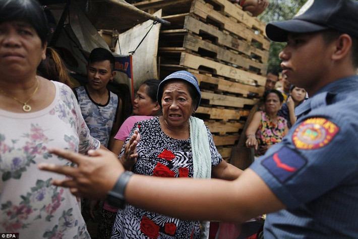 Một người phụ nữ Philippines lớn tuổi hoảng sợ khi nhìn thấy một thi thể bên ngoài nhà.