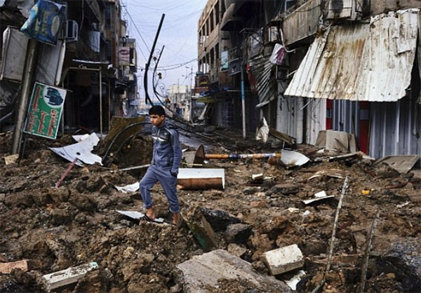 Một thanh niên đứng giữa đống đổ nát trên con đường ở thành phố Mosul.