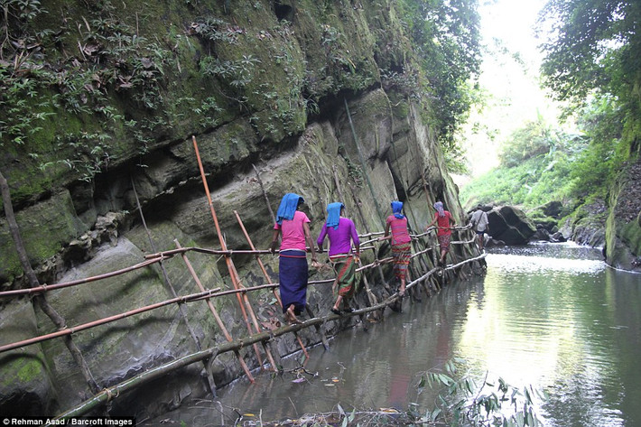 Ngôi làng của những bộ lạc ở Bangladesh này nằm sâu trong những quả đồi ở huyện Bandarban. Họ vẫn duy trì lối sống truyền thống và tách biệt với thế giới hiện đại. Ảnh: Những người phụ nữ bản địa ở Bangladesh đi qua một cây cầu tạm bợ để lấy nước từ một con suối trên đồi.