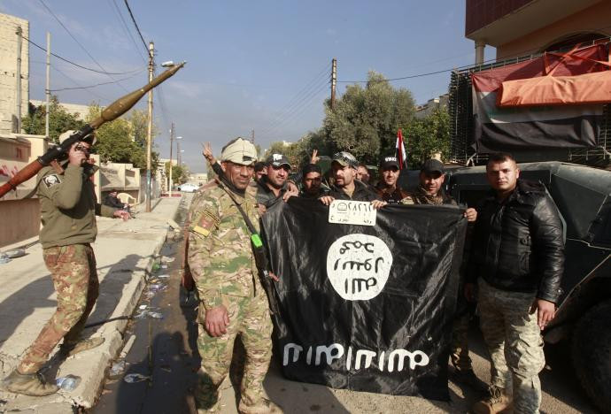 Các thành viên lực lượng Iraq cầm lá cờ của phiến quân IS vừa bị hạ xuống trên đường phố Mosul ngày 8/1.