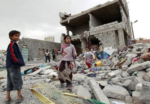 Một số em nhỏ Yemen đứng trước tòa nhà đổ nát.