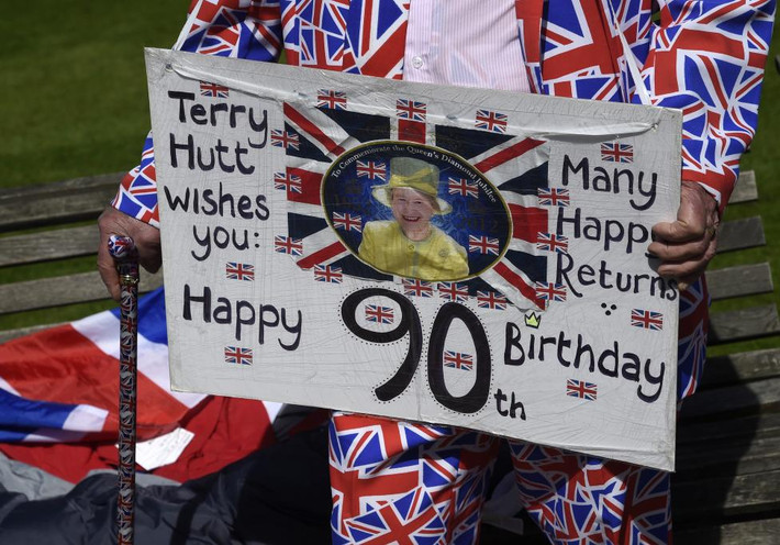 Terry Hutt cầm tấm biển chúc mừng sinh nhật lần thứ 90 của Nữ hoàng Elizabeth bên ngoài lâu đài Windsor ở Windsor hôm 20/4.