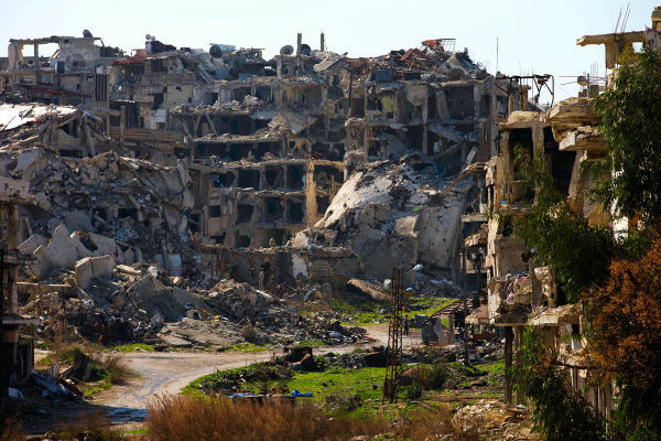 Cuộc nội chiến Syria đã tàn phá nặng nề quốc gia Trung Đông này và khiến khoảng 4,8 triệu người dân Syria phải sơ tán. Ảnh: Một người đàn ông Syria đi qua những tòa nhà đổ nát ở Homs ngày 26/2/2016.