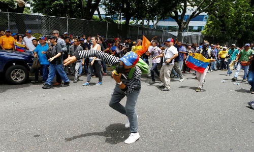 Một người biểu tình ném đá về phía cảnh sát chống bạo động Venezuela.