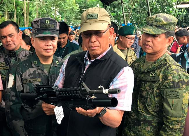 Bộ trưởng Quốc phòng Philippines Delfin Lorenzana kiểm tra một khẩu súng hiện đại tịch thu được của phiến quân Maute khi thăm một doanh trại quân đội ở Marawi ngày 8/6. Ảnh: Reuters.