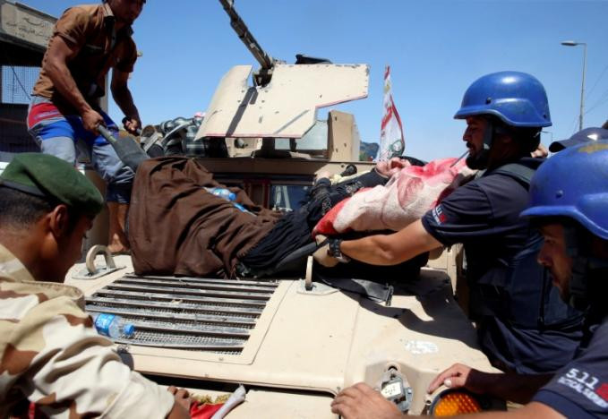Nhân viên y tế đưa một phụ nữ nằm trên cáng xuống xe quân sự ở Tây Mosul ngày 23/6. Ảnh: Reuters.