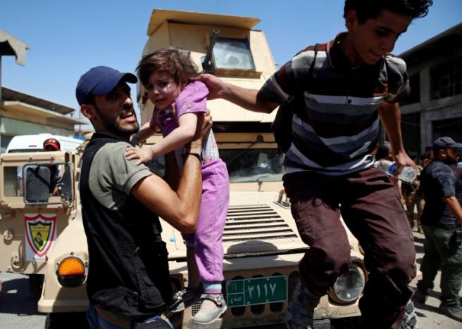 Nhân viên y tế bế một bé gái xuống ở Tây Mosul hôm 23/6. Ảnh: Reuters.