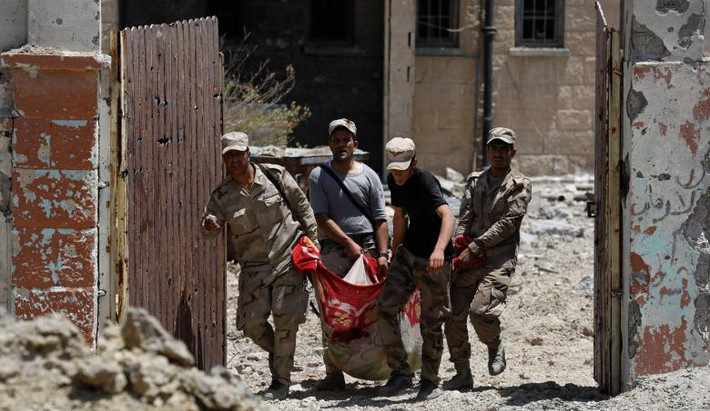 Các binh sĩ Iraq khiêng một đồng đội bị thương trong cuộc giao tranh gần khu Thành cổ Mosul.
