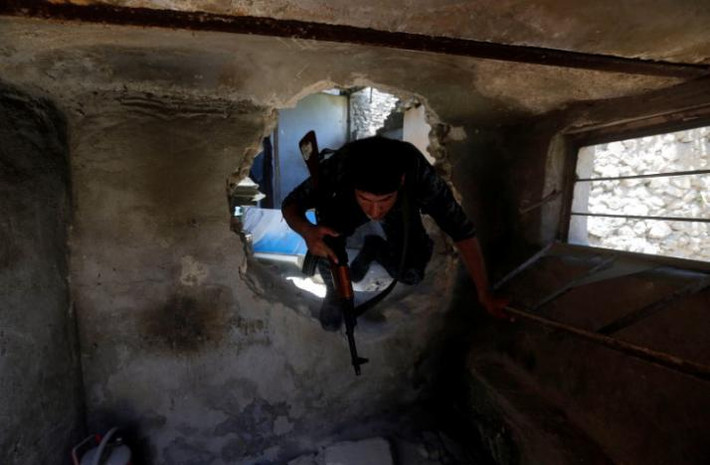 Cảnh sát Iraq trèo qua lỗ hổng trên tường vào căn nhà đổ nát ở Thành cổ Mosul.