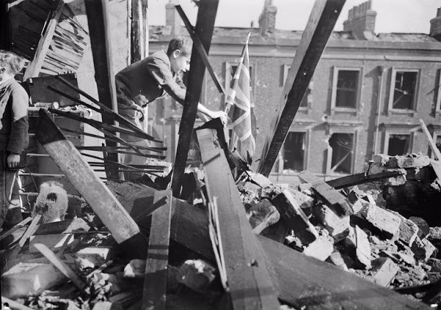 Bé trai cắm cờ trước ngôi nhà đã bị phá hủy trong một đợt không kích ở London năm 1940. Ảnh: VT.