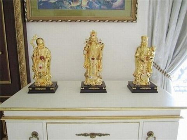 Bộ tượng Phúc - Lộc - Thọ bằng vàng, nạm ngọc được đặt trên mặt tủ cao.