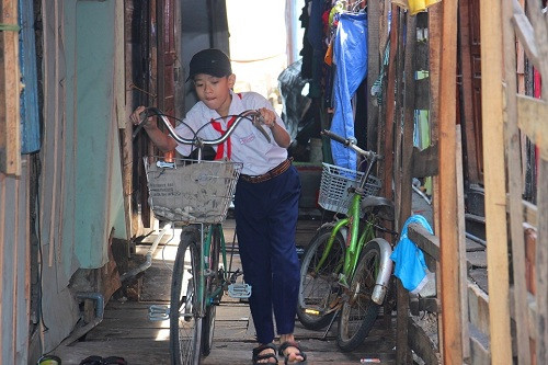 Trẻ em ở đây khó khăn di chuyển trên những tấm ván chật hẹp đến lớp. Ảnh: Dũ Tuấn