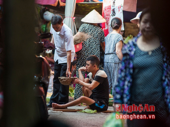 Cũng ở chợ này, tại vị trí khác, một thanh niên đang ngồi xin tiền ngay giữa đường.