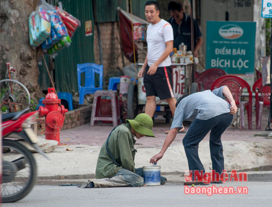 Theo thống kê của Sở Lao động, Thương binh và Xã hội, trên địa bàn tỉnh có khoảng hơn 110 người lang thang ăn xin, tập trung chủ yếu ở Thành phố Vinh. Những 'cái bang' thời hiện đại này không chỉ "hành nghề" ở các chợ, bệnh viện mà còn ở các ngã ba, ngã tư hoặc trên nhiều đoạn đường. Trong ảnh là một thanh niên với dáng vẻ hai chân bị dị tật, lết đi xin tiền trên đường Đặng Thái Thân.