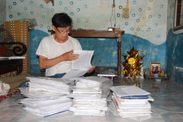 Ông Lộc cùng đống đơn thư được tính bằng kg để đi đòi bồi thường oan sai. Ảnh: Ngọc Vũ