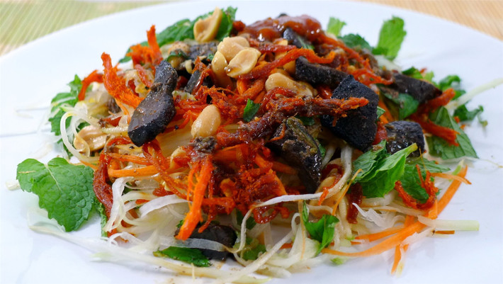 Nộm bò khô Ai cũng thích nộm bò khô, ai cũng thích được ăn cái món trộn này vào buổi chiều, và công bằng mà nói thì món nộm bò khô chỉ nên ăn từ xế chiều trở đi. Bạn không thể ăn nó vào buổi sáng thay bún phở, cũng chẳng nên ăn nó vào buổi trưa bởi nó chẳng… giải quyết được gì cho cơn đói của bạn. Vậy nên thời điểm đẹp nhất để ăn nộm là buổi chiều, và đúng vào khoảng thời gian xế chiều đó, ăn nộm mới thấy ngon hơn cả. Nộm Hà Nội gồm có đu đủ thái sợi, các loại rau thơm, rồi thì thịt bò khô cắt nhỏ và rắc thêm một ít lạc rang. Tùy vào các hàng khác nhau mà lại có thêm các nguyên liệu khác nhau, có hàng thì cho thêm gan rán, rồi thịt bò khô mỏng, thịt bò khô miếng dày, có hàng lại trộn thêm với chim quay, có hàng thì thêm vào vài miếng dạ dày. Chua chua, cay cay, giòn giòn, dai dai,.. bạn có thể ăn 1, ăn hai đĩa nộm mà chẳng sợ ngấy hay đầy bụng.