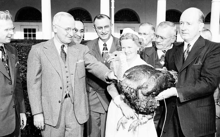 Cựu Tổng thống Harry Truman mỉm cười khi chuẩn bị nhận con gà tây từ các thành viên của Hội đồng gia cầm và trứng quốc gia và các đại diện khác của ngành công nghiệp thịt gà bên ngoài Nhà Trắng vào năm 1949.